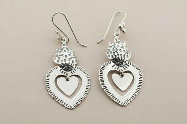 Silver heart-shaped earrings on a dark gray background