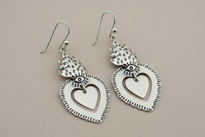 Silver heart-shaped earrings on a dark gray background