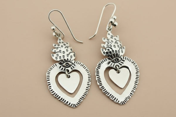 Silver heart-shaped earrings on a dark gray background