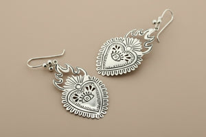 Silver heart-shaped earrings on a dark gray background