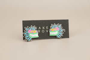 Pair of colorful mask-shaped earrings on a black card with 'MAKER ROW' branding.