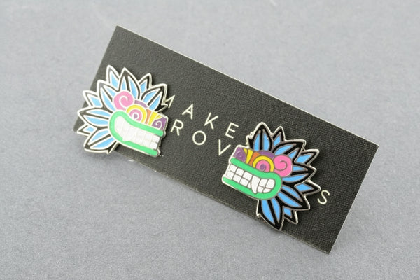 Two colorful pins on a black card with 'MAKE ROV' text, on a gray background