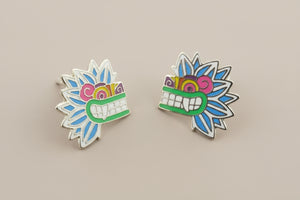 Pair of colorful mask-shaped earrings on a gray background