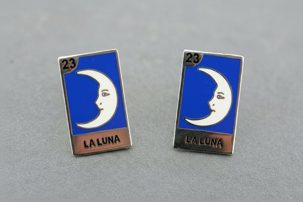 Pair of 'La Luna' earrings with blue background and silver border on a gray surface