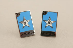 Pair of 'La Estrella' earrings with star design on a gray background