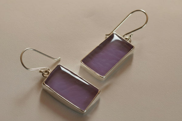 Purple rectangular earrings with silver hooks on a light gray background