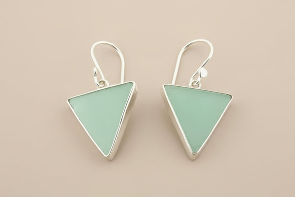 Pair of triangle-shaped earrings with light green stones on a gray background