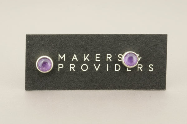 Pair of purple gemstone earrings on a 'Makers & Providers' card against a light gray background