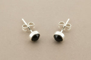 Pair of silver earrings with black stones on a gray background
