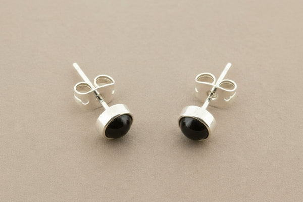 Pair of silver earrings with black stones on a gray background