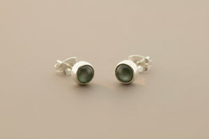 Pair of silver stud earrings on a gray background