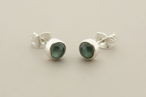 Pair of silver stud earrings with gemstones on a gray background