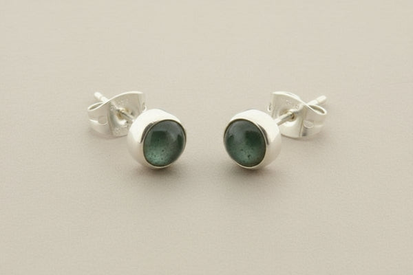 Pair of silver stud earrings with gemstones on a gray background