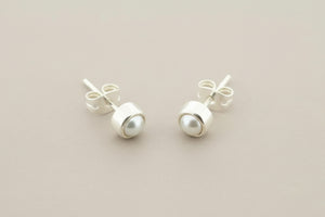 Pair of pearl stud earrings on a gray background