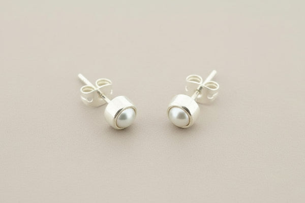Pair of pearl stud earrings on a gray background