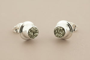 Pair of silver earrings with gemstone-like centers on a gray background