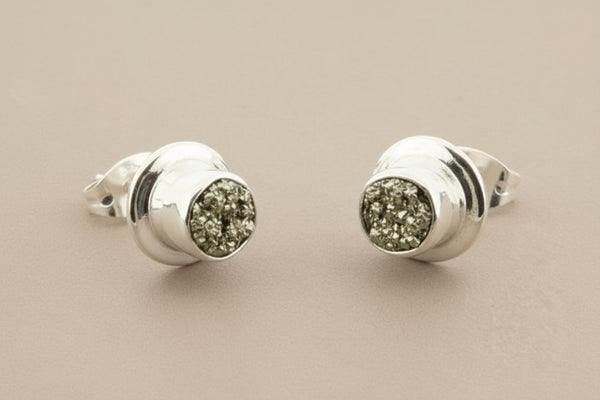 Pair of silver earrings with gemstone-like centers on a gray background