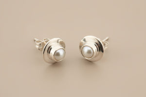 Silver earrings with pearl centers on a gray background