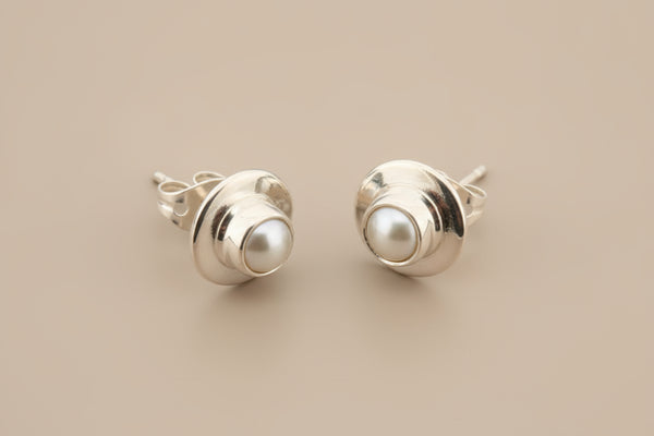 Silver earrings with pearl centers on a gray background