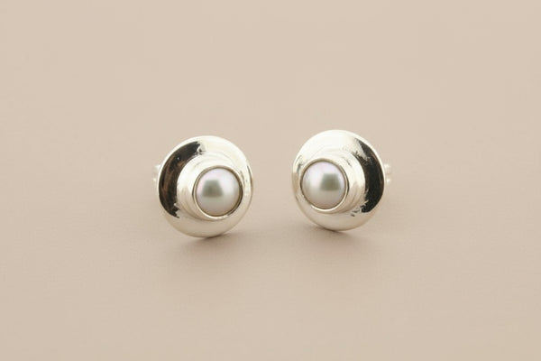 Pair of silver earrings with pearl centers on a gray background