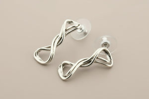 Silver earrings with a twisted design on a gray background