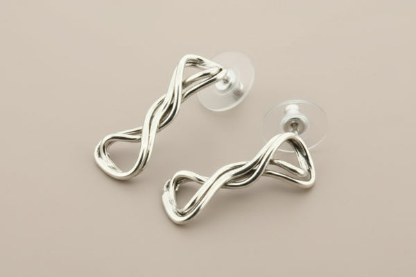 Silver earrings with a twisted design on a gray background