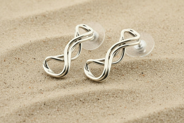 Silver earring with a twisted design on a gray background