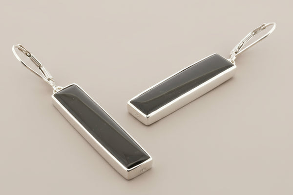 Pair of silver earrings with black stones on a gray background