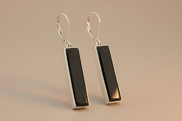 Pair of black rectangular earrings on a gray background