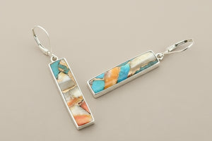 Pair of earrings with colorful stone inlay on a gray background