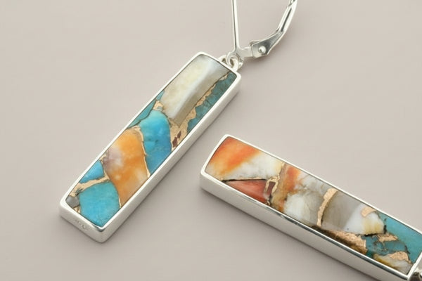 Pair of earrings with colorful stone inlays on a gray background