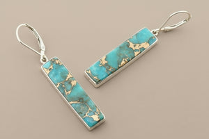 Turquoise bar earrings with gold accents on a gray background
