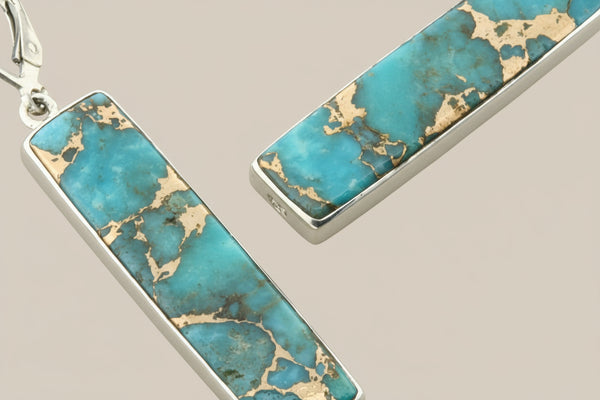 Turquoise and gold bar-shaped earrings on a gray background