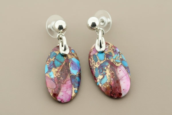 Pair of earrings with colorful stone drops on a gray background