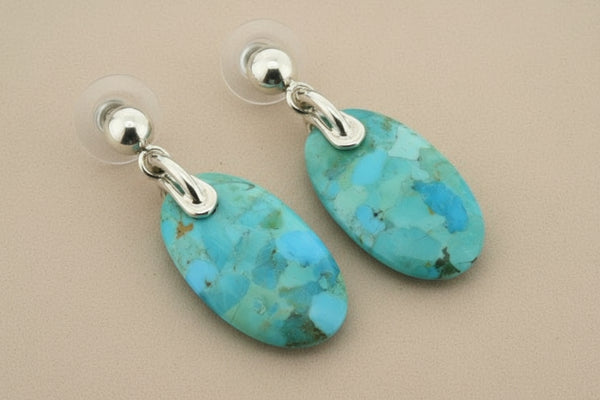 Turquoise stone earrings with silver hooks on a dark background