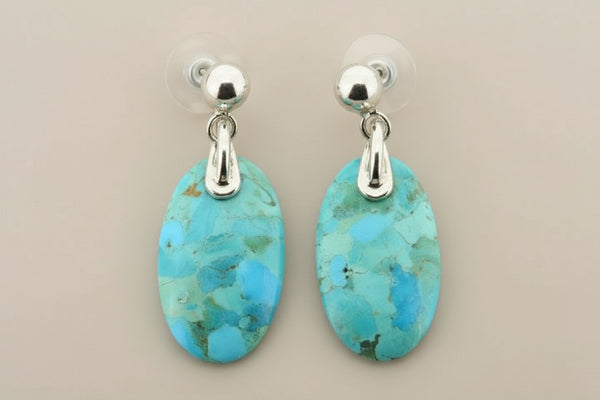 Turquoise earrings with silver hooks on a gray background