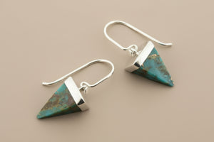 Pair of silver and turquoise triangle-shaped earrings on a gray background