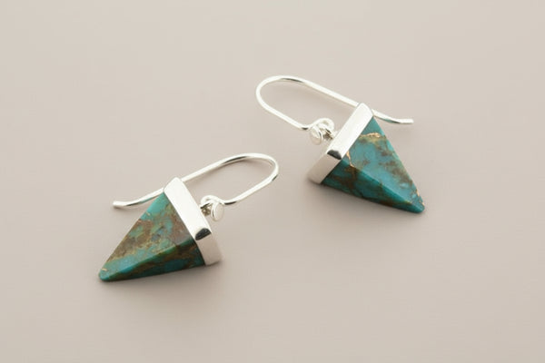 Turquoise triangle earrings with silver accents on a gray background