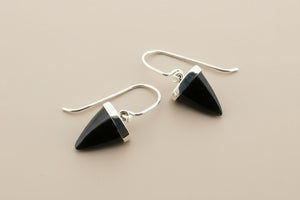 Black triangle earrings with silver hooks on a gray background