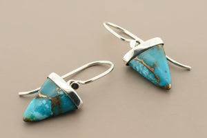 Turquoise triangle earrings with silver hooks on a gray background
