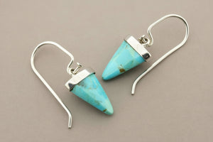 Turquoise cone-shaped earrings with silver hooks on a gray background