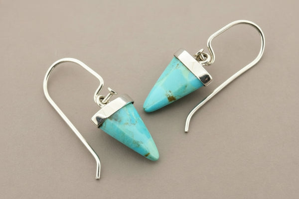 Turquoise cone-shaped earrings with silver hooks on a gray background