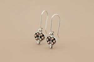 Silver earrings with rose gold accents on a gray background