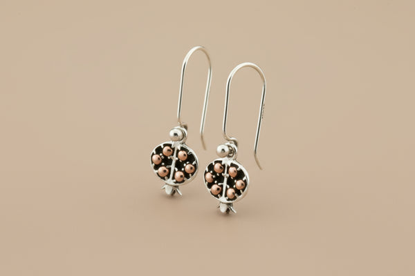 Silver earrings with rose gold accents on a gray background