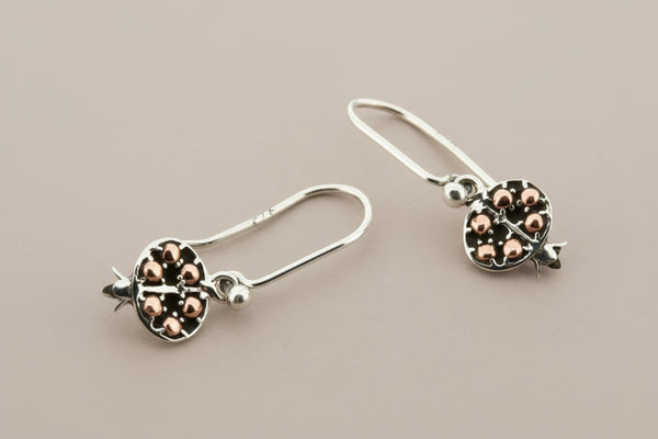 Pair of silver earrings with rose gold accents on a gray background