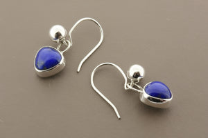Silver earrings with heart-shaped blue stones on a gray background