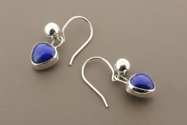 Silver earrings with heart-shaped blue stones on a gray background