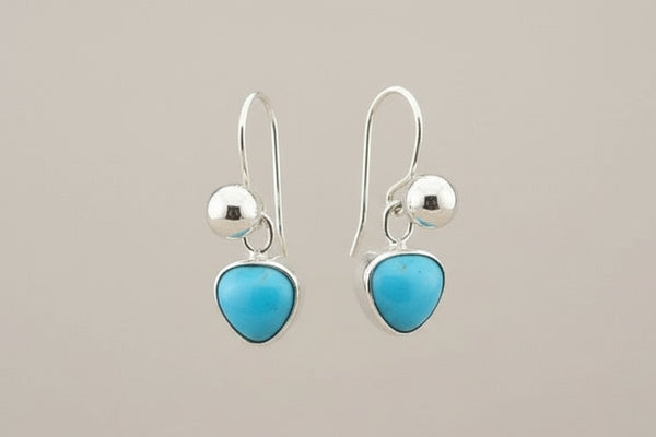 Pair of silver earrings with turquoise stones on a gray background