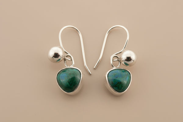 Silver earrings with green gemstones on a gray background