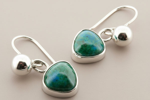 Pair of earrings with green gemstones and silver hooks on a gray background